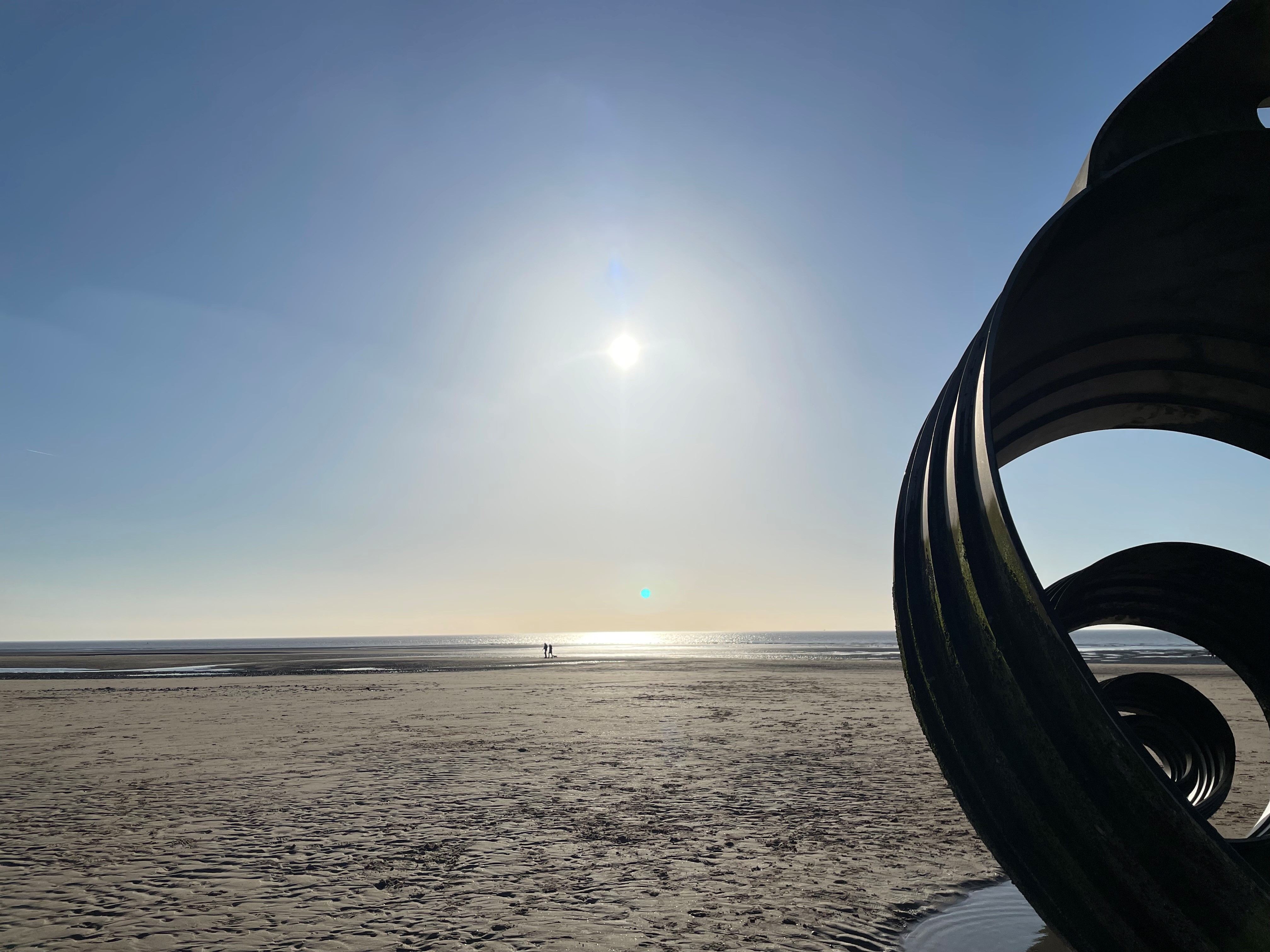 Cleveleys beach showing the sand, the sun setting and Mary&#039;s shell installation