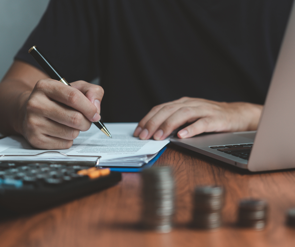 Image of man writing with coins and calculator on the table