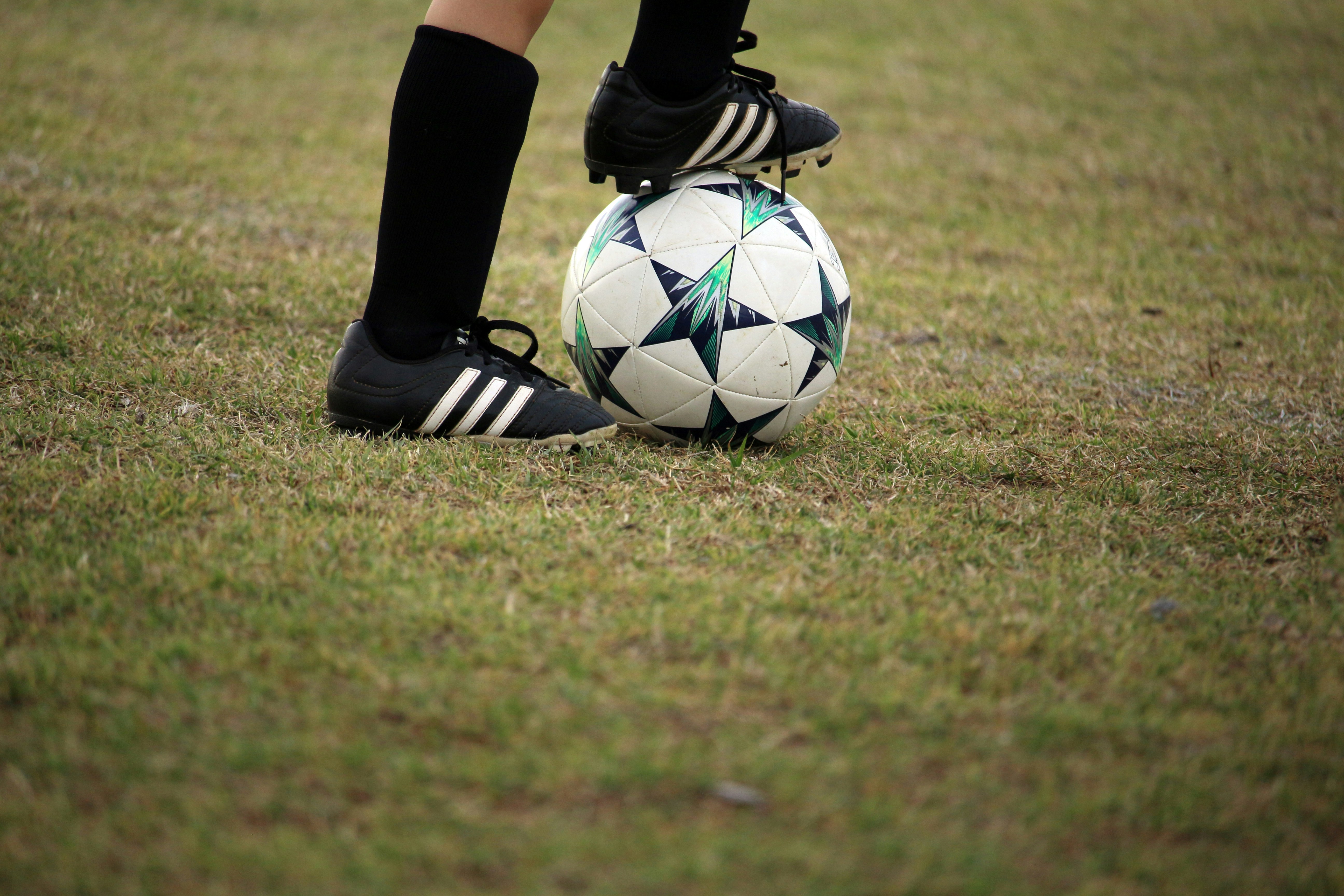 Someones legs wearing football boots. They&#039;re putting their right foot on a football boot.