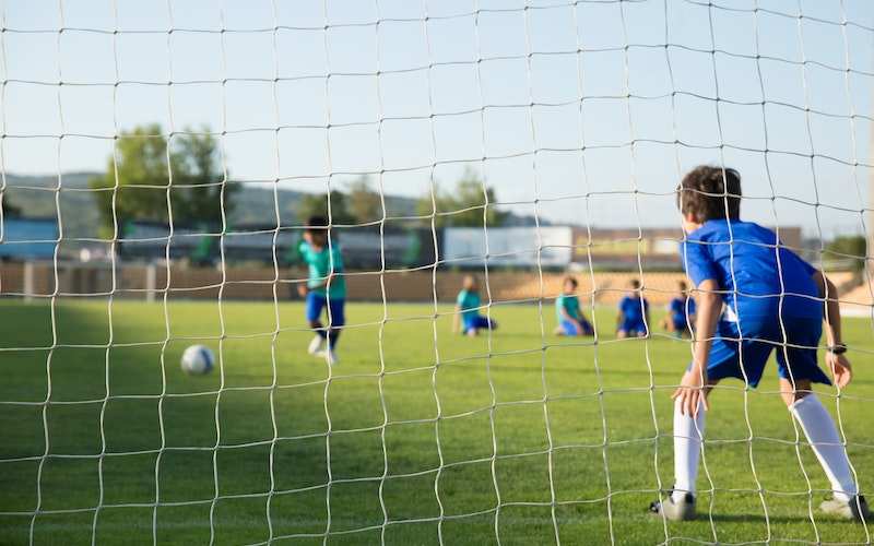 Young boy in goal during outdoor football game.