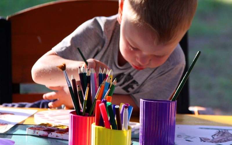 Young boy colouring in with colouring pencils.