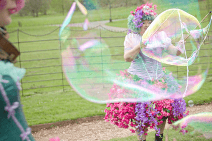 Woman in a floral dress blowing large bubbles.