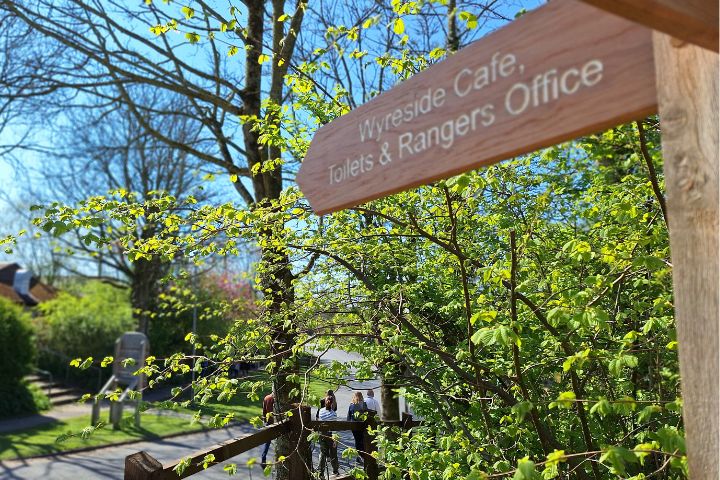 A wooden sign post pointing to the Wyreside Cafe, Toilets and Rangers Office.