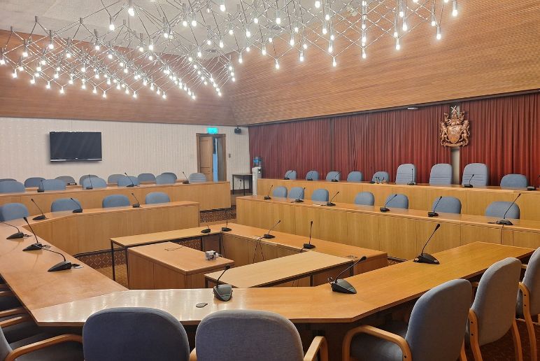 A large room with rows of tables and chairs in a square formation.