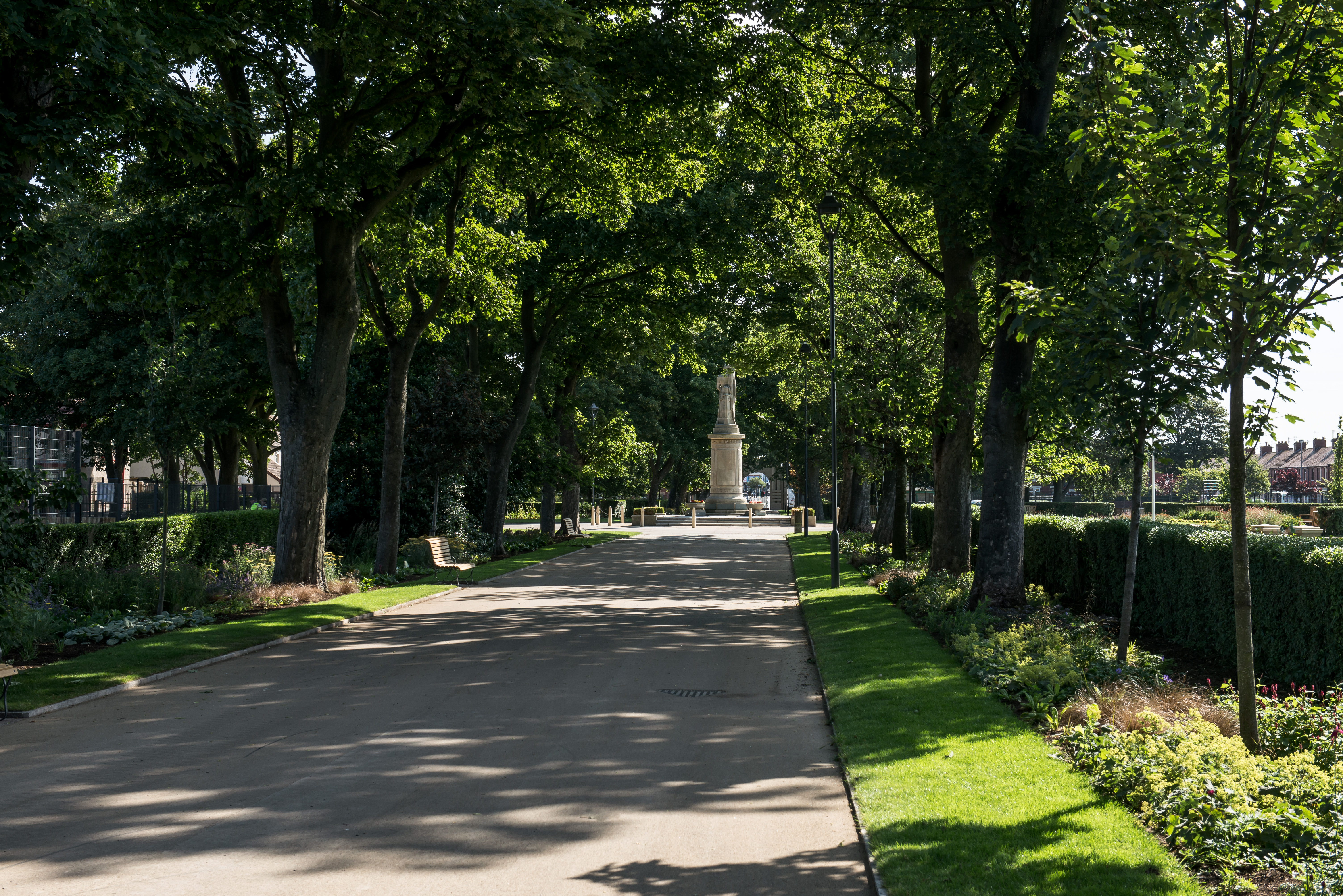 Tree lined path with statue at the end on a sunny day in Memorial Park.
