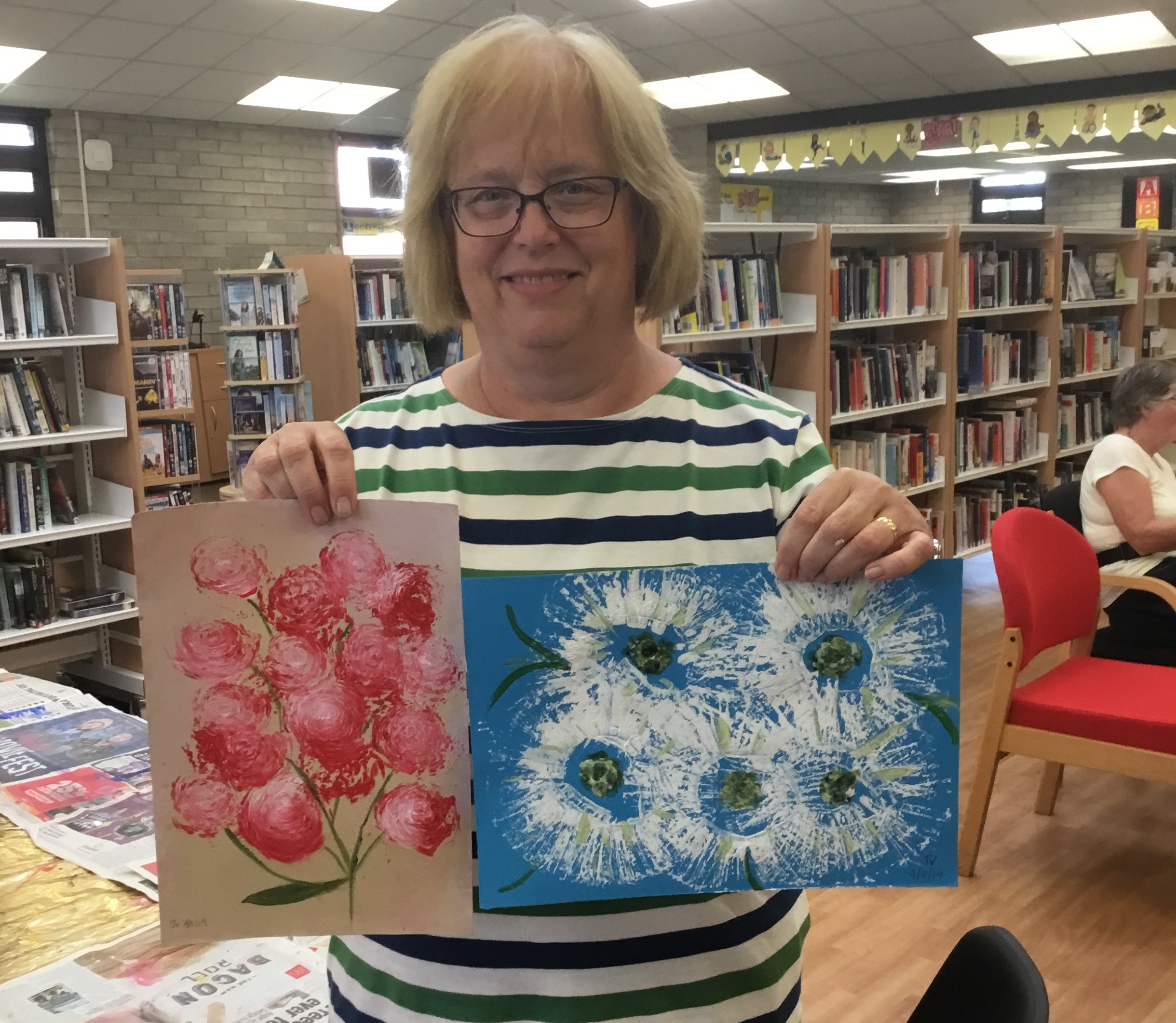 Woman holding paintings done at the fun arts group