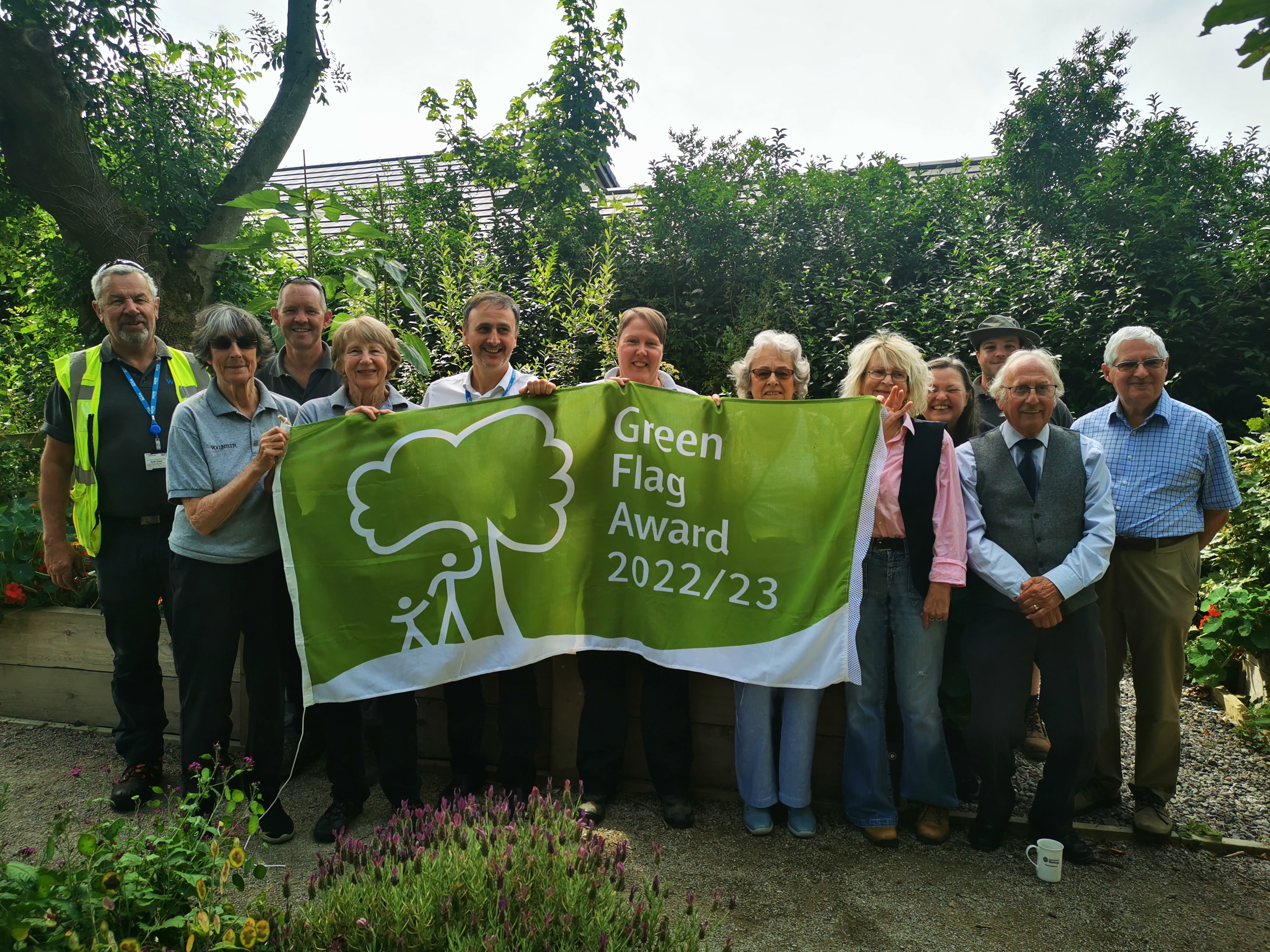 People stood in garden holding green flag award