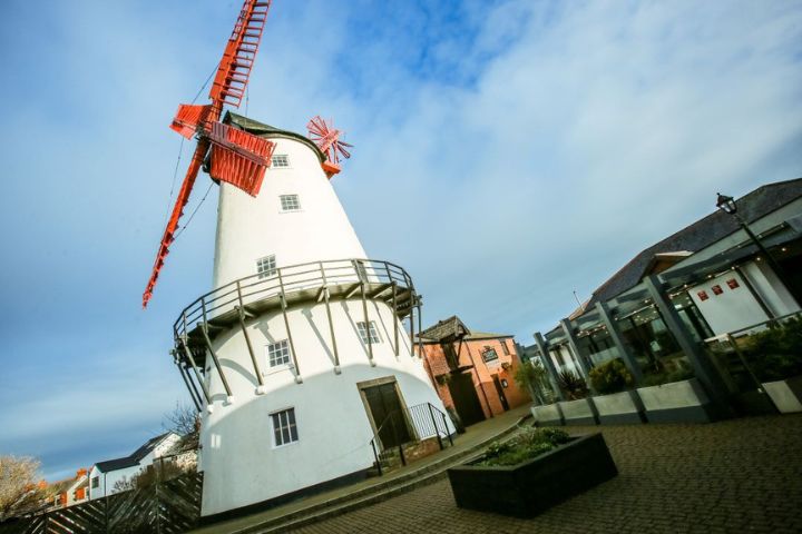 Marsh Mill, Thornton. A tall white windmill with orange blades.