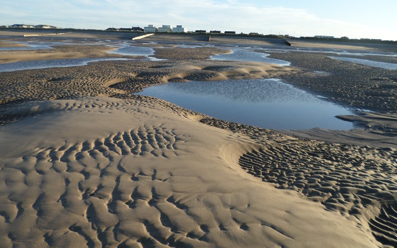 Cleveleys beach view with sand and pools of water.