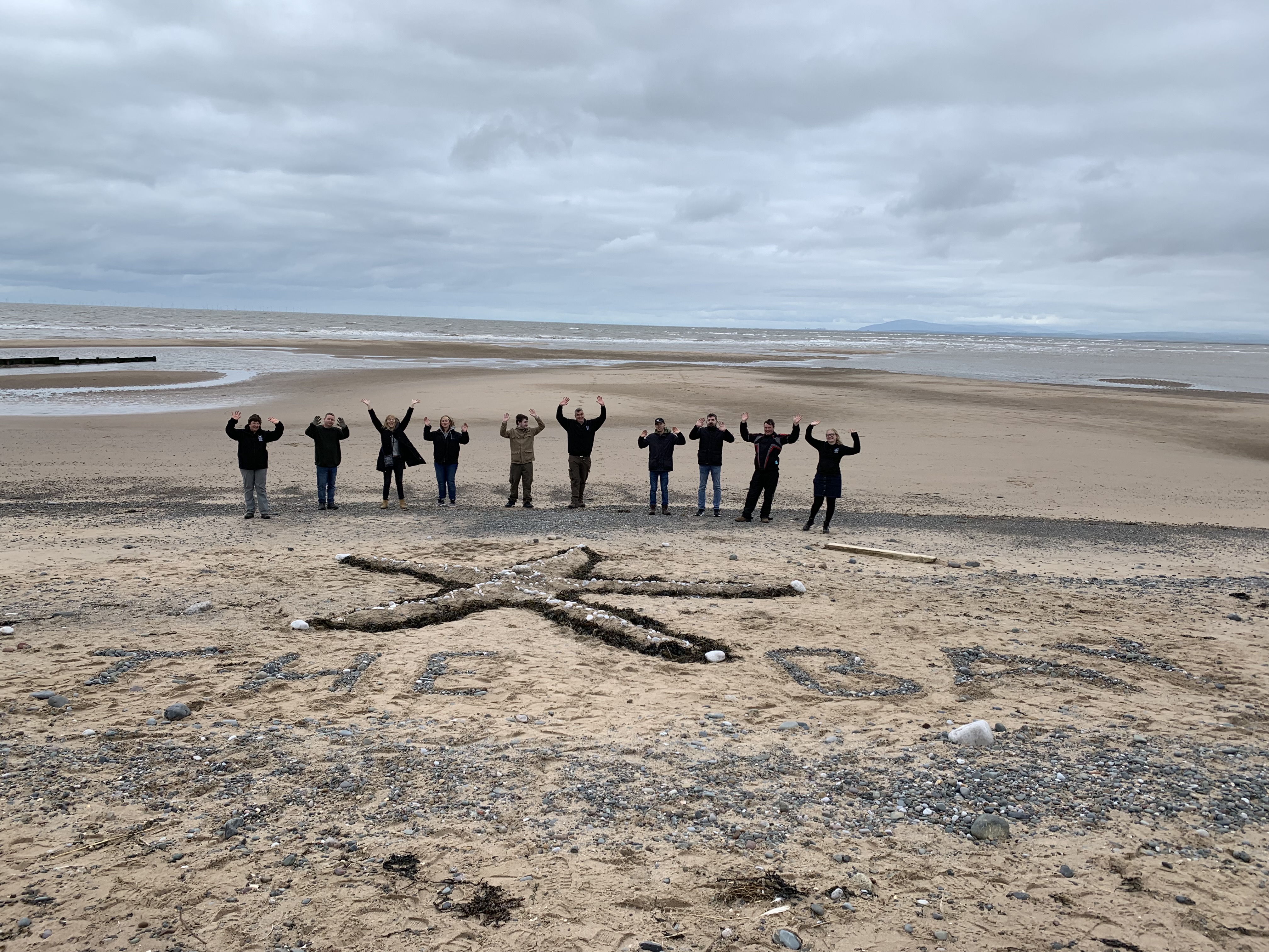 A group of people on a beach taking part in wellbeing activities