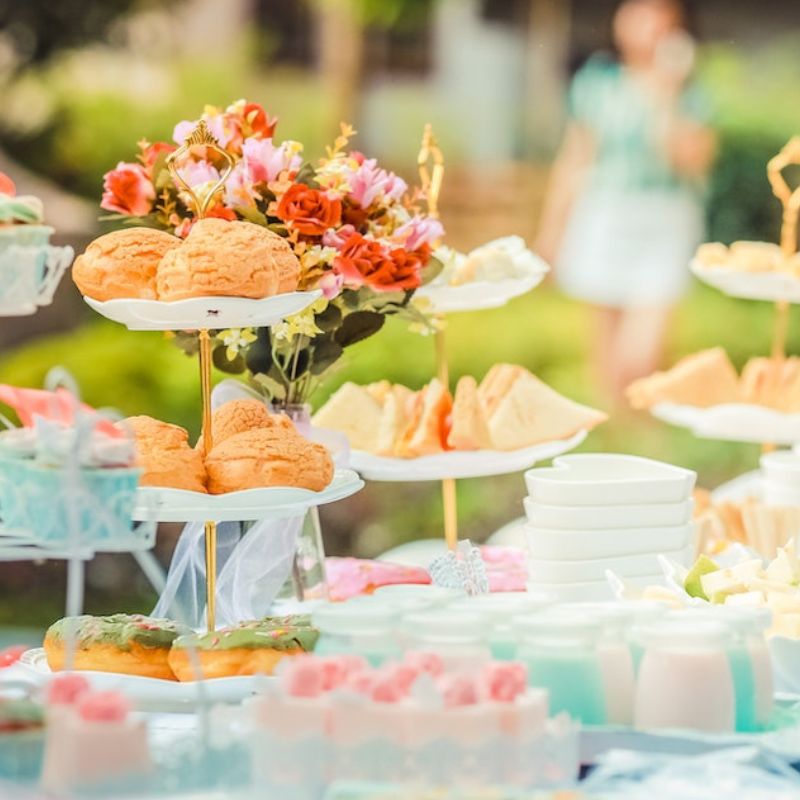 Cakes and pastries set our on a table during an outdoor party.