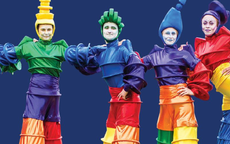 Stilt walkers in colourful costumes posing for camera.