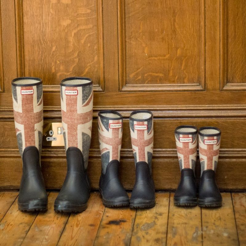 Welly boots of different sizes with union jacks on them, lined up in a row in a hallway.