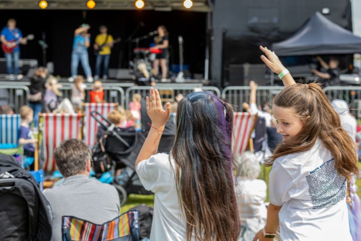 Two children with their backs to the camera. They're swaying their hands while watching a live performance at Wyre's Wanderland Festival 2025.