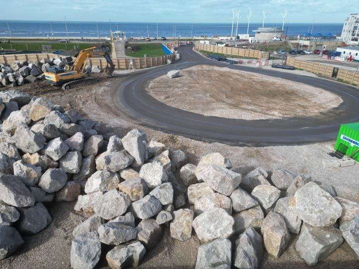 A hydraulic excavator laying boulders along Wyre's beachfront.