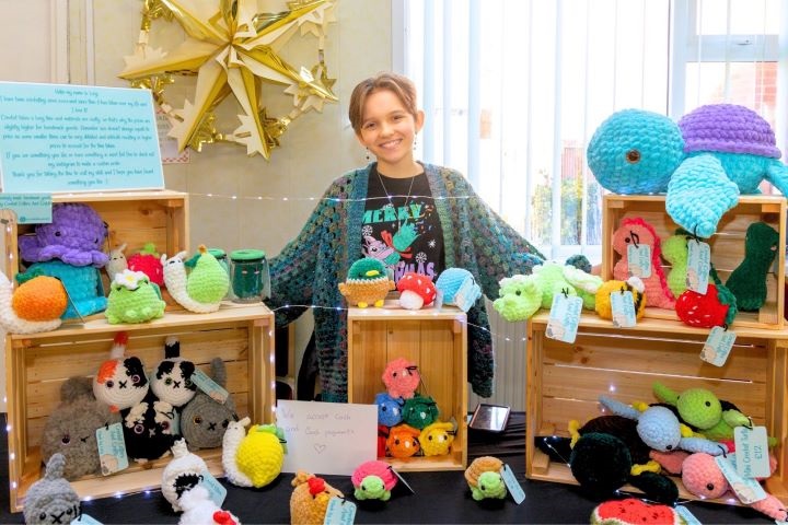 A young person smiling in front of their stall.