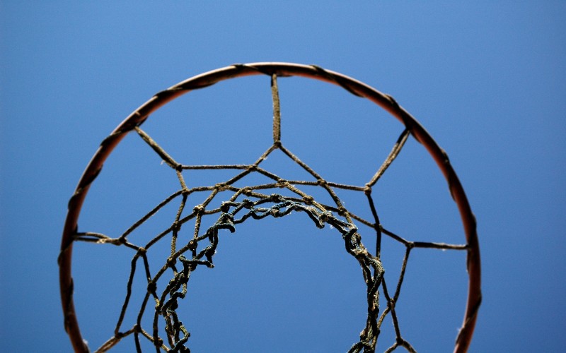 Looking up at a netball hoop with blue sky background.