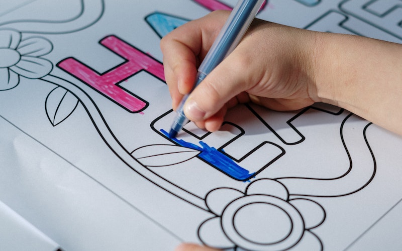 Close up of child's hand colouring in a Happy Easter drawing.