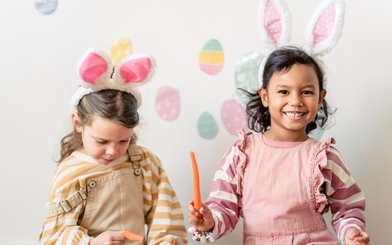 Two young girls wearing bunny ears smiling for camera.