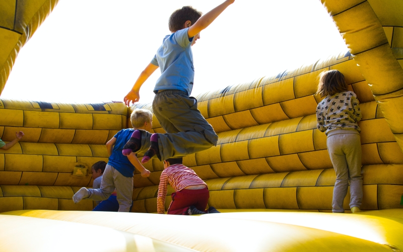 Children bouncing on a bouncy castle outdoors.