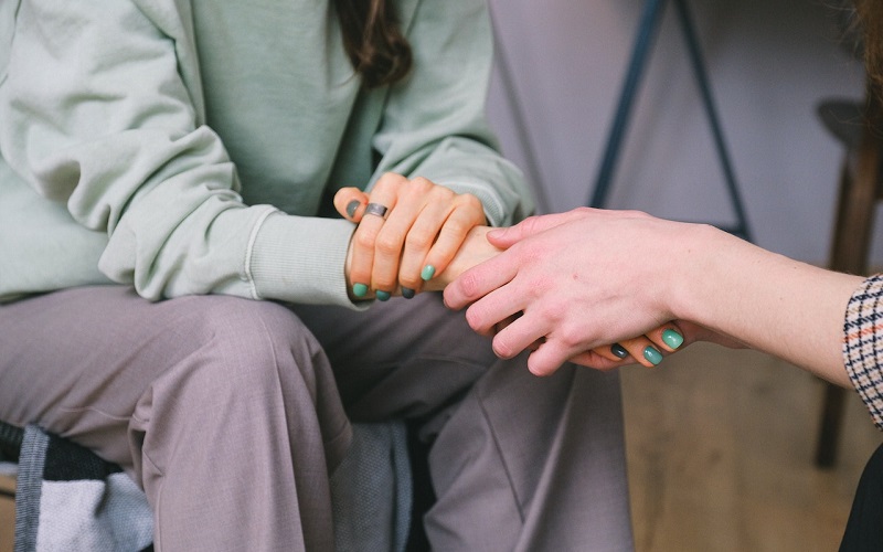 Woman holding the hand of another woman in support.