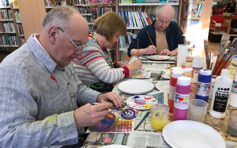 Three people taking part in a library art and craft session.