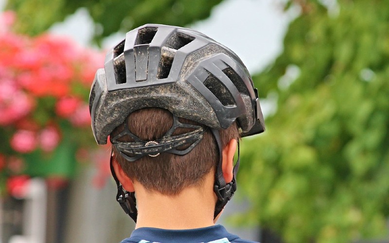 Back of boy&#039;s head wearing a bicycle helmet.