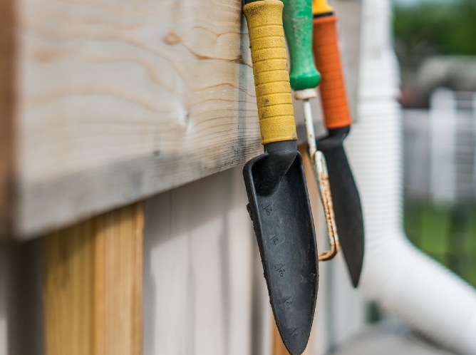 Gardening trowels hung on a fence.