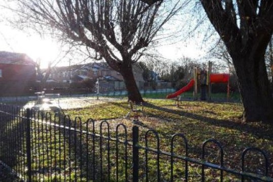 Trees and red slide in children's play area at Farnham Way.