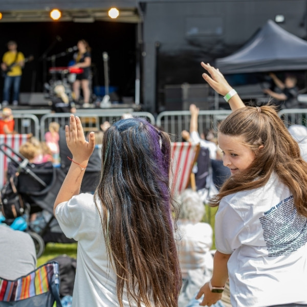 People in a crowd waving at the musicians on stage.