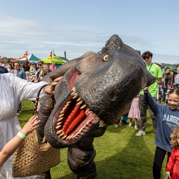 People petting a T-Rex dinosaur.