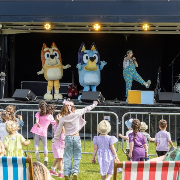 A crowd in front of a stage where BBC's Bluey and her sister Bingo are performing.